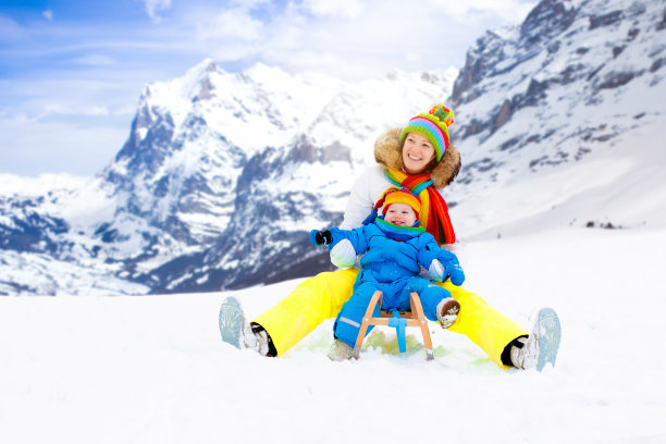 母亲和婴儿坐在雪橇上。冬天下雪好玩。图片下载
