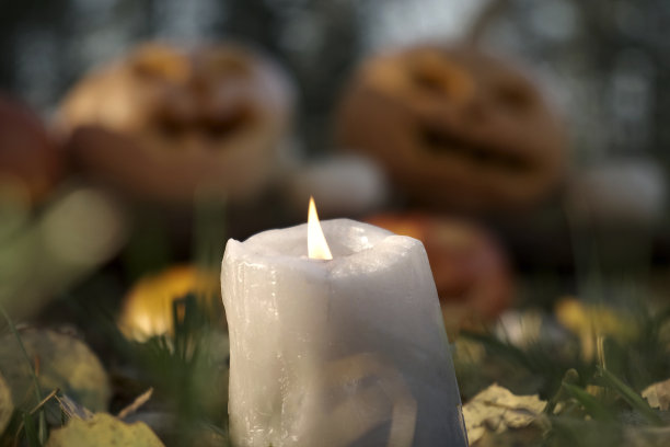 万圣节南瓜灯背景上的燃烧蜡烛特写图片下载