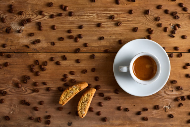 咖啡饮料在杯子里，洒的豆子和饼干在桌子上图片下载