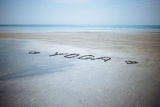 用鹅卵石和贝壳写在沙滩上的瑜伽特写图片下载