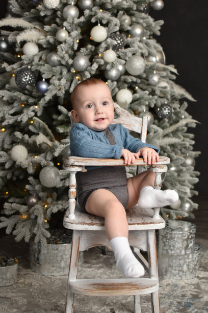 1岁的宝宝坐在带有圣诞树的婴儿高脚椅上图片下载