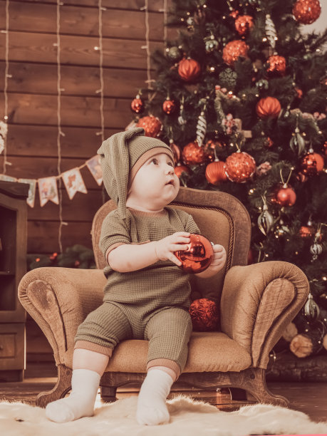 1岁的宝宝坐在有圣诞树的扶手椅上图片下载