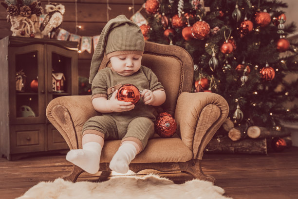 圣诞快乐，节日快乐。可爱的小婴儿在圣诞装饰的房子里。孩子过得很愉快。深色背景下的婴儿肖像。图片下载
