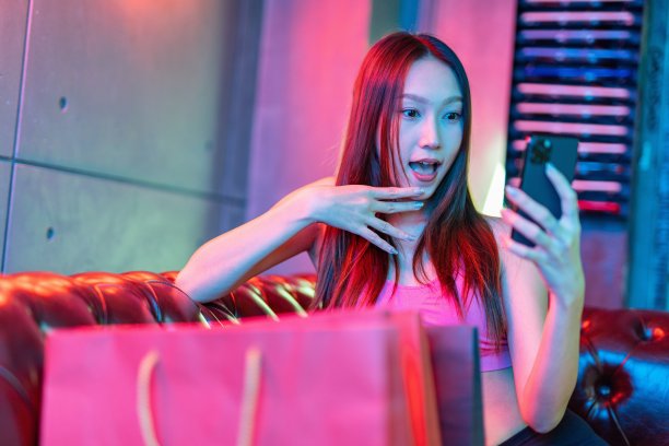 肖像照片的年轻美丽的亚洲女模特在霓虹灯房间聊天愉快的她的手机购物狂欢后图片下载