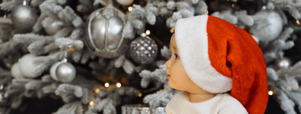 圣诞快乐，新年快乐。圣诞背景上戴着圣诞帽的可爱婴儿肖像。有放置文字的横幅图片下载