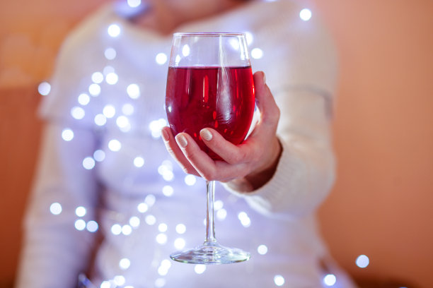 女手拿着闪亮的红酒酒杯，特写。本空间图片下载