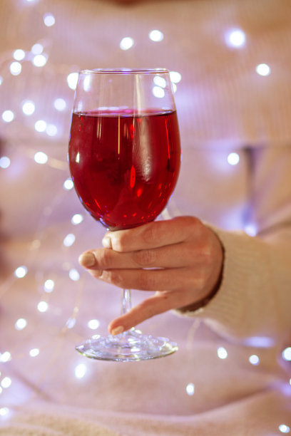 女手拿着闪亮的红酒酒杯，特写。本空间图片下载