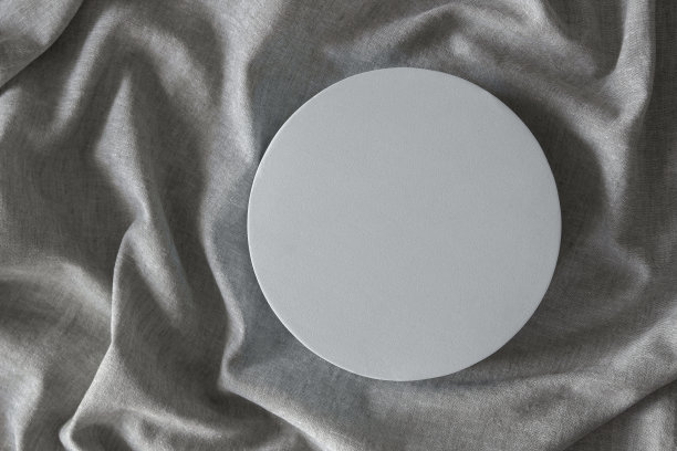 空白圆形台架，用于展示化妆品或产品，背景为天然灰色亚麻面料。俯视图图片下载