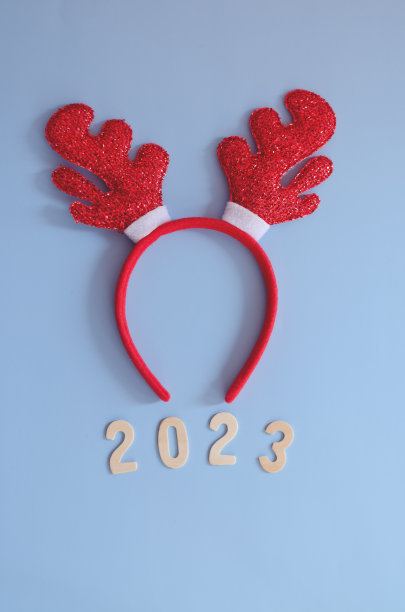 数字2023的俯视图。红色卡通鹿角特写。蓝色背景。新年，庆祝圣诞图片下载