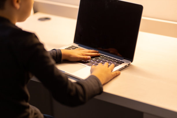 一个男孩使用空白屏幕的笔记本电脑的特写图片下载