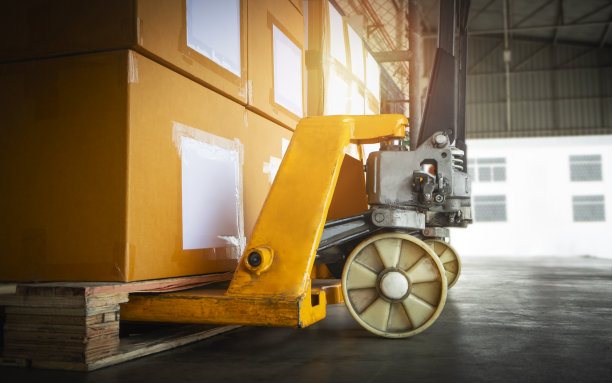 托盘上堆放包装盒的手动托盘车。采购产品手动升降机，托盘千斤顶装载机纸箱，纸板箱。装运货物。运输、货物、物资、仓库、物流。图片下载