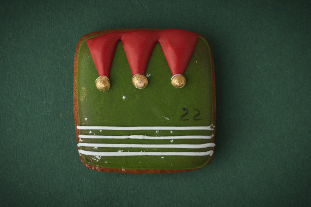 来自降临节日历的美味圣诞饼干，让你在期待圣诞节的时候数着日子。姜饼饼干，绿色背景上有节日糖霜。圣诞快乐，新年快乐图片下载