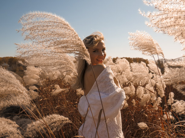 一个美丽的女人，在一个温暖的秋日里，穿着低垂的白衬衫，赤裸着后背站在田野里图片下载