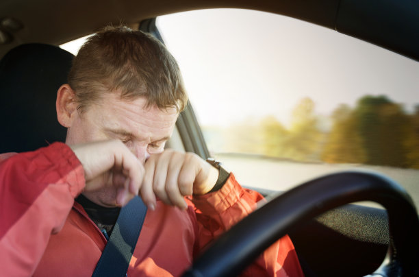 疲劳的司机一边开车一边用手揉眼皮。图片下载