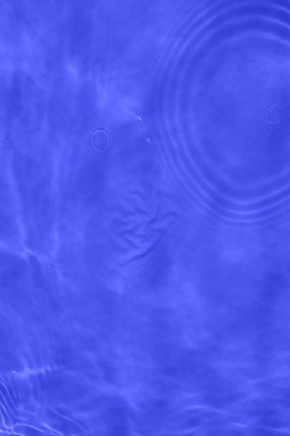 离焦模糊透明蓝色清澈平静的水面纹理与飞溅和气泡。新潮抽象的自然背景。阳光下的水波与复制空间。蓝色水彩闪闪发光图片下载