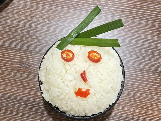 一碗用辣椒做眼睛、鼻子和嘴巴的米饭上的面部表情。图片下载