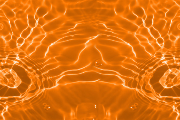 离焦模糊透明橙色清澈平静的水面纹理与飞溅和气泡。新潮抽象的自然背景。阳光下的水波与复制空间。橙色水闪闪发光图片下载