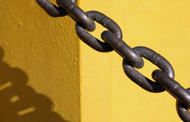 特写老生锈的链子与阴影在黄色背景图片下载