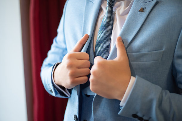 新郎在婚礼前的准备工作。领带和夹克。手的特写图片下载