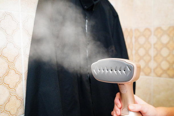 妇女手中衣物的便携式蒸笼。背景黑色衬衫图片下载