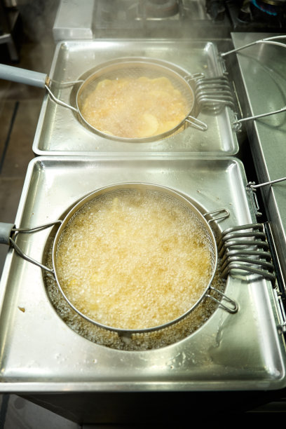 两个炸锅在餐厅厨房里煎土豆，垂直照片图片下载