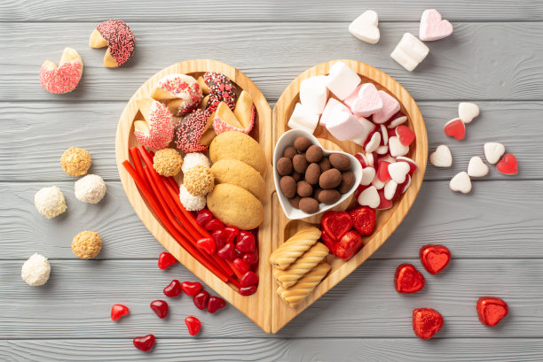 情人节庆祝概念。俯视照片的木制心形服务托盘与糖果碟子糖果和饼干在灰色的木制桌子背景图片下载