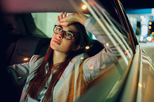 疲惫的商务女性坐在汽车或出租车的后座上图片下载