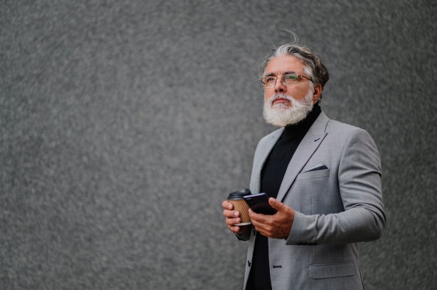 资深商人站在外面，用着智能手机喝着咖啡图片下载