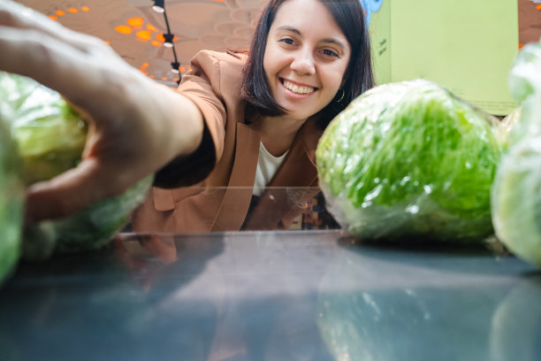 寻找蔬菜的妇女从货架上取下产品一对顾客购物清单图片下载