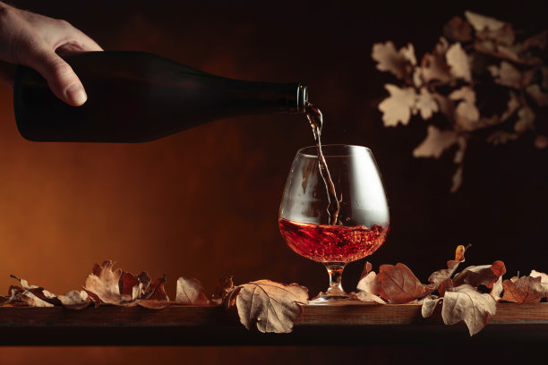 白兰地从瓶子里倒进玻璃杯里。图片下载