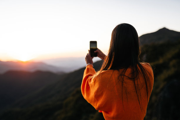 在山上拍摄日落的女人图片下载