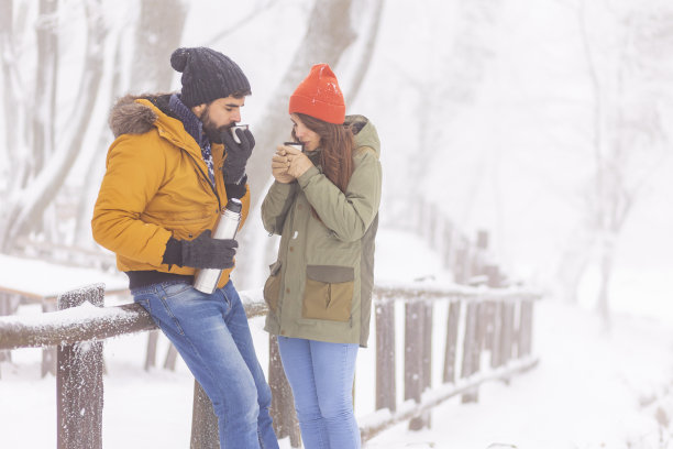 在雪天的户外，一对夫妇喝着热茶，放松身心图片下载