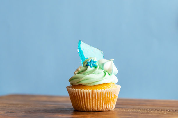 自制的蓝色纸杯蛋糕放在木桌上。冬天和圣诞节的主题，雪花在奶油和蓝色的冰。新鲜和家庭烘焙的甜蜜。图片下载