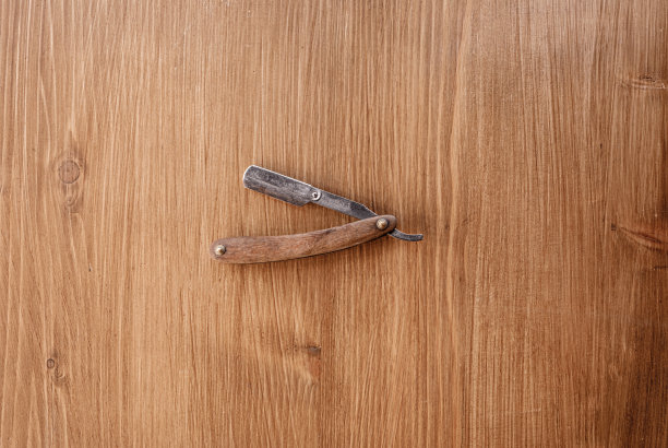 复古直剃刀与木制手柄孤立在木制背景。专业的理发店工具。放置文本的地方图片下载