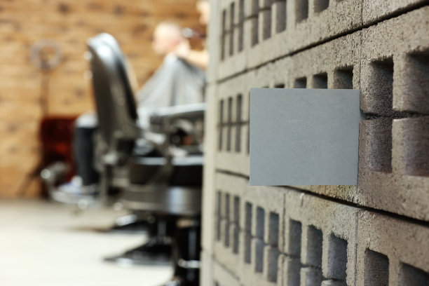 灰色明信片或老板卡与模拟时尚理发店或美容院的背景。模糊的理发师正在给顾客剪胡子。图片下载