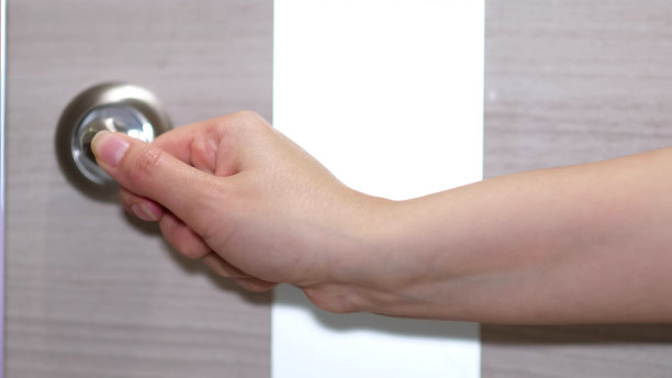 侧视图一个女人进入一个明亮的房间，迈出第一步。一个女性的手打开一扇有金属把手的白色门的特写。图片下载