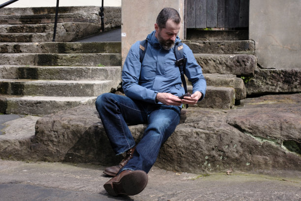 一个男人正在看他的智能手机。图片下载