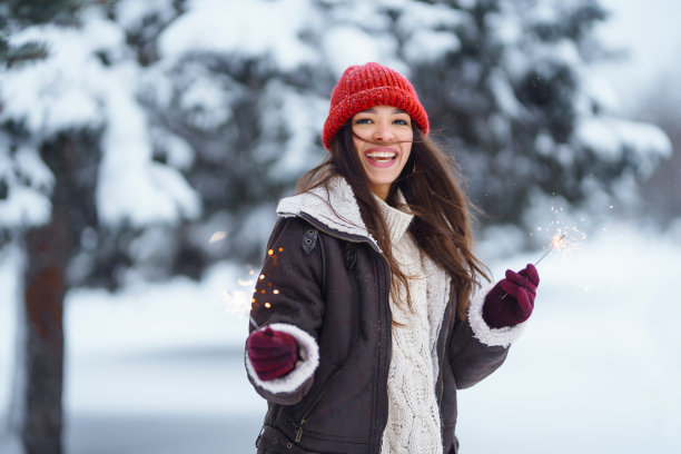 时髦的女人手里拿着孟加拉灯，在雪景中享受和享受着寒假。图片下载