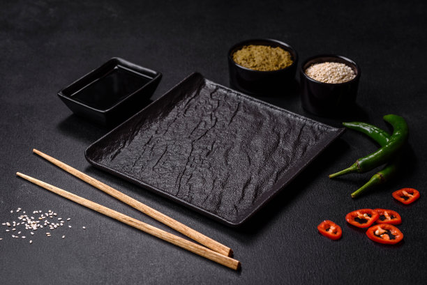 黑色的混凝土背景上，空盘子里放着亚洲食物的木棍图片下载