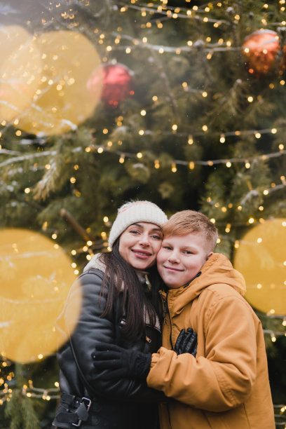 白人母子穿着温暖舒适的衣服走在节日的城市街道上。图片下载