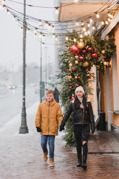 白人母子穿着温暖舒适的衣服走在节日的城市街道上。图片下载