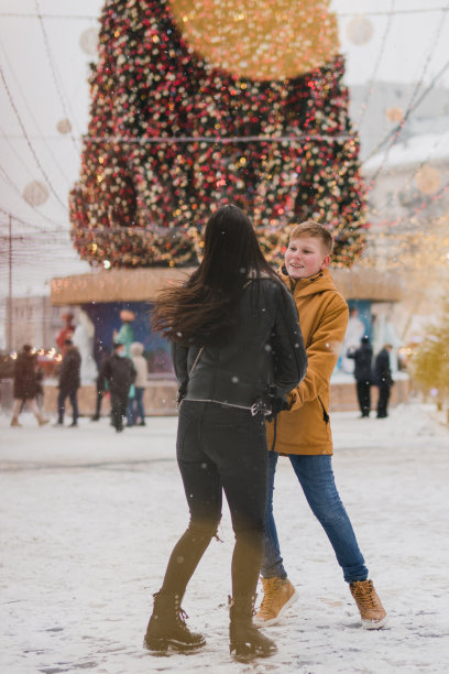 白人母子穿着温暖舒适的衣服走在节日的城市街道上。图片下载