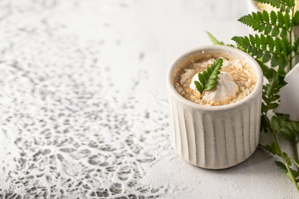 白色陶瓷杯，热巧克力装饰，鲜奶油，蛋白饼干和绿叶。冬季饮料概念。图片下载