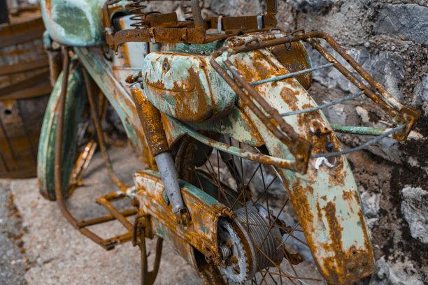 在石头楼梯的背景下，一辆生锈的青绿色旧摩托车被拆解了。一辆老式两轮车生锈的细节特写。图片下载