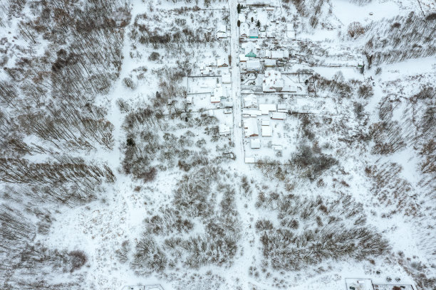 乡村景观，小雪覆盖的村庄在冬季森林。无人机拍摄的照片。图片下载