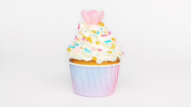 纸杯蛋糕装饰奶油与黄金洒和华夫饼花在光的背景。香草松饼在一个粉红色渐变纸杯特写。儿童聚会的甜食和甜点。图片下载