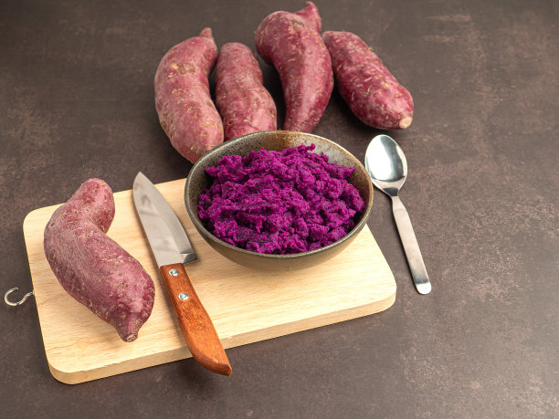紫色的山药堆，紫色的红薯泥放在盘子里，刀放在砧板上，背景是棕色的图片下载