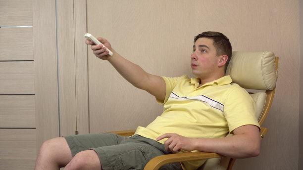 因为太热，年轻人打开了空调。一个人在闷热的房间里挥舞着双手。图片下载