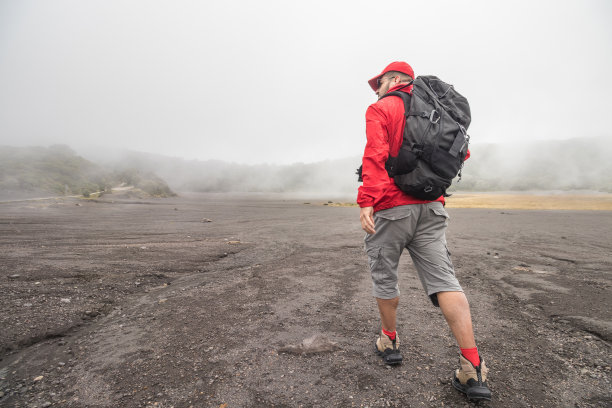 在伊拉祖火山国家公园，一个背包和防水夹克的徒步旅行者在雾中行走图片下载