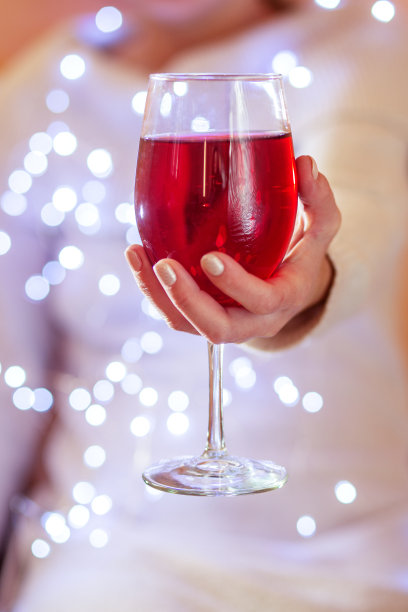 女手拿着闪亮的红酒酒杯，特写。本空间图片下载
